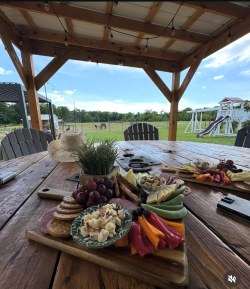 A charcuterie board of Southern cheeses and cured meats set out beside wine glasses on the farm